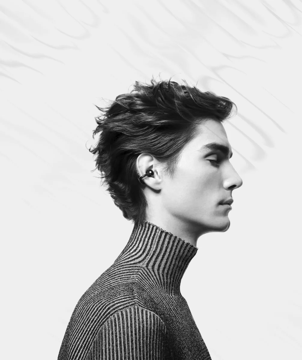 Portrait of a young man in profile wearing a ribbed turtleneck and an earbud